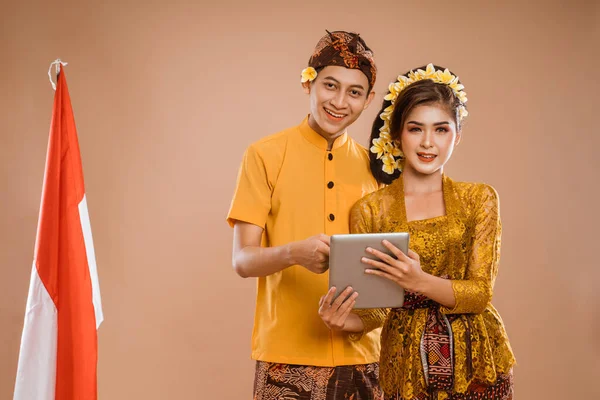 happy balinese couple using tablet pc together over isolated background