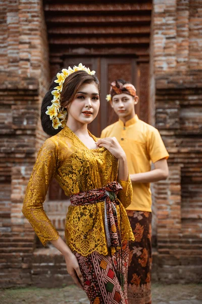 balinese couple portrait wearing kebaya dress standing in front of traditional bali gate