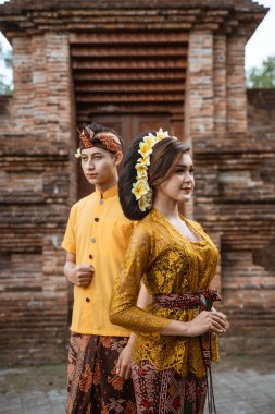 balinese couple portrait wearing kebaya dress standing in front of traditional bali gate