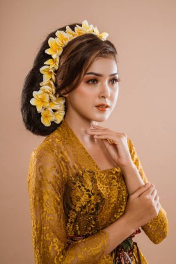 beauty portrait of beautiful balinese woman in kebaya isolated over brown background