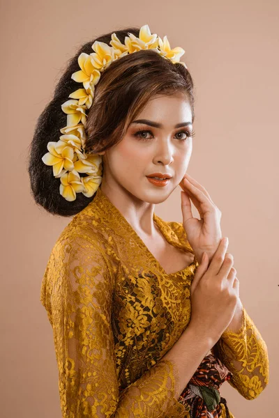 beauty portrait of beautiful balinese woman in kebaya isolated over brown background