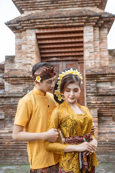 balinese couple portrait wearing kebaya dress standing in front of traditional bali gate