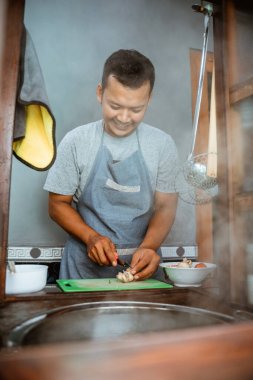 the seller slices the toppings while preparing the dish on the cart