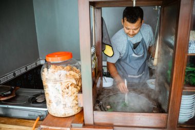 the seller boils the vegetables while preparing the dish on the cart