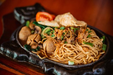 fried chicken noodle dish on a hot plate with chicken and meatball topping on the table