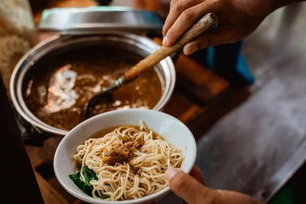 close up of sellers hand prepare noodles in a bowl when preparing dishes on the cart