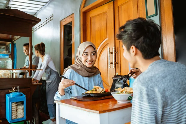 a couple of customers enjoy chicken noodles and chicken fried noodles at a stall