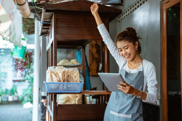 Excited Saleswoman Apron Hands Clenched While Using Tablet Cart Background — Stok fotoğraf