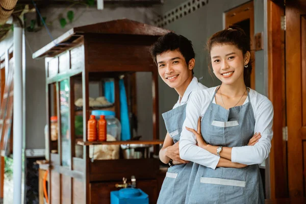 female and male waiters smiling with hands crossed on chicken noodle cart background