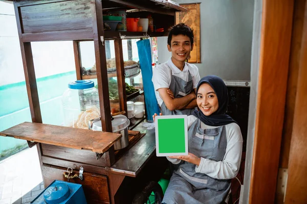 a couple of sellers in aprons show tablet screens when using a tablet in a stall cart