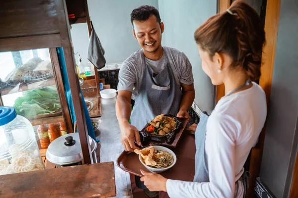 sellers and waiters prepare chicken noodles and fried noodles on a tray