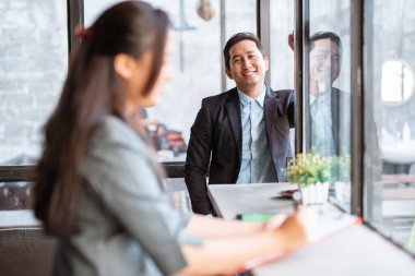 happy businessman smiling while looking at camera, his partner in the foreground