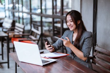 happy smiling young business woman working with her laptop in the coffee shop by herself