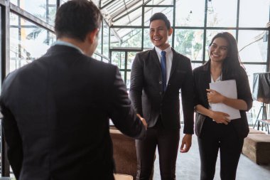 happy two young business partner and executive shaking hands in the cafe