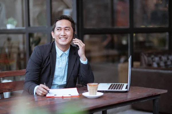 Smiling Asian Businessman Having Phone Call While Working Alone Cafe — Zdjęcie stockowe