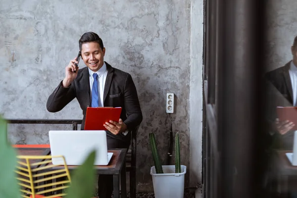 busy businessman having a discussion through his phone while working with laptop