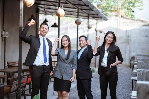 excited team of business people raised their arm and looking at the camera