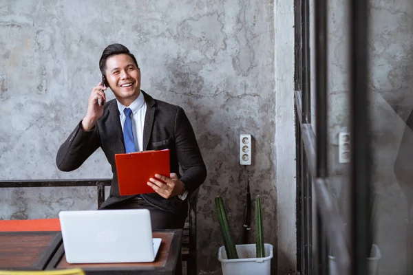 busy businessman having a discussion through his phone while working with laptop
