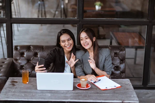 Две Привлекательные Азиатки Работницы Проводят Видеоконференцию Используя Смартфон Сидя Кафе — стоковое фото