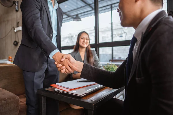 happy two young business partner and executive shaking hands in the cafe