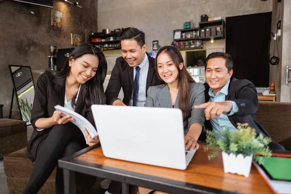portrait of asian business people meeting in a cafe using laptop