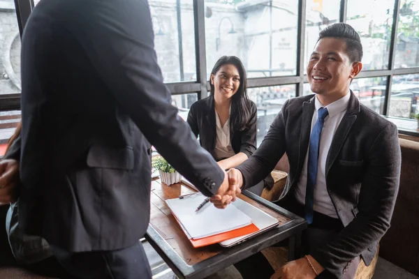 happy two young business partner and executive shaking hands in the cafe