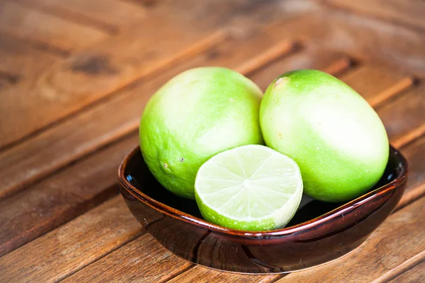 Fresh lime wholes and slice on wood background — Stock Photo, Image