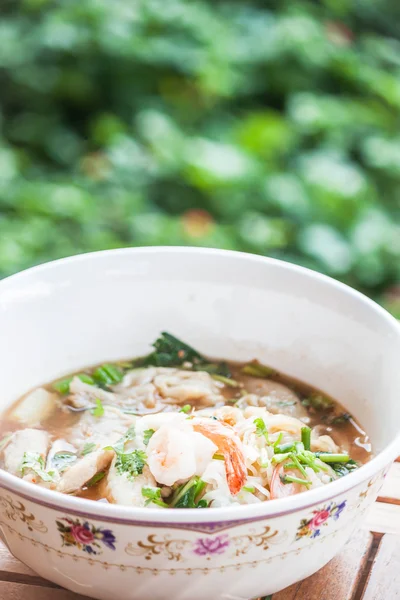 Thaise spicy noedels soep met varkensvlees en garnalen op houten tafel — Stockfoto