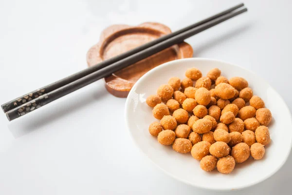 Spicy peanuts snack and chopsticks on white table — Stock Photo, Image