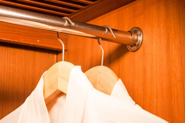 White bathrobe hanging on wood hanger in closet — Stock Photo, Image