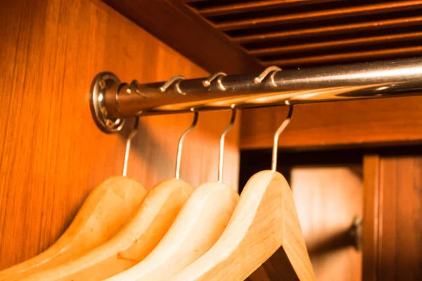 Empty wooden hanger hanging in a wood wardrobe — Stock Photo, Image