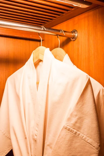 Witte gewaden met houten kleerhangers in hotel kast — Stockfoto