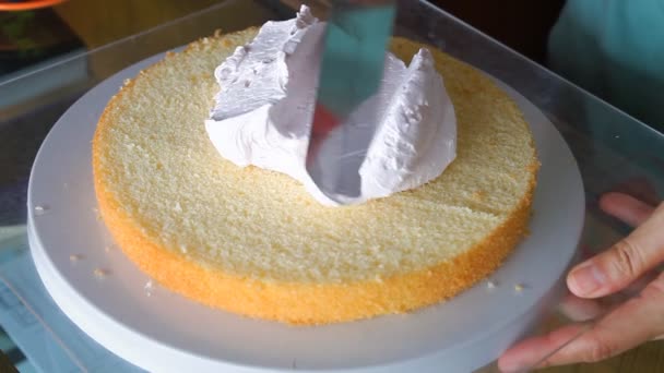 Baker decorating cake layer with whipped cream — Stock Video