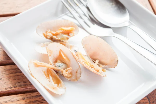 Перемешать жареные моллюски чили пасты на белой тарелке с ложкой — стоковое фото