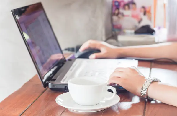 Femme utilisant un ordinateur portable avec une tasse de café — Photo