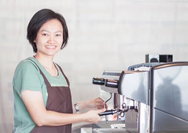Asian barista smiling and making cup of coffee