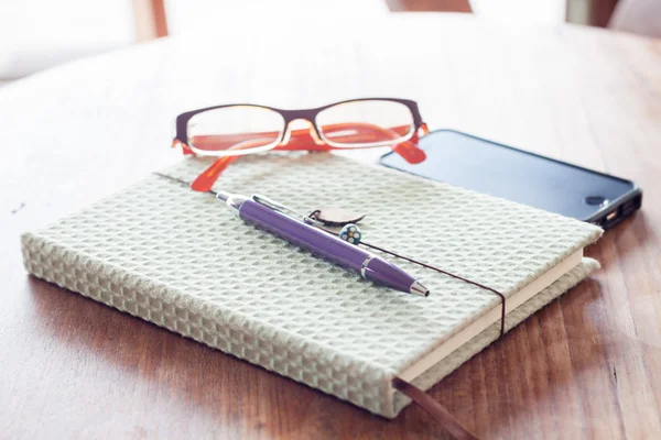 Notebook és a toll, a fából készült asztal smartphone — Stock Fotó