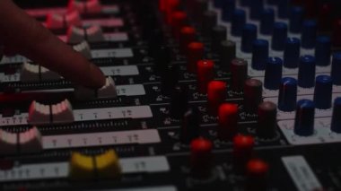DJ, profesyonel bir yönetmenin ses konsolundaki farklı kanalların ses seviyesini değiştirir. Yakın çekim.