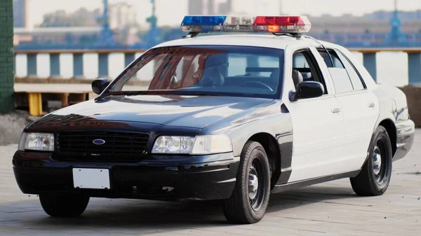 Şehir merkezinin arka planında işaret fişeği olan Amerikan polis arabası.
