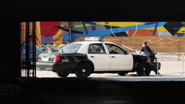 女性警察官が犯罪者を逮捕する。警察の車の近くに銃を持った女の子 — ストック動画