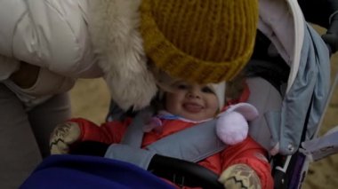 Annem sokakta şapkalı gülümseyen küçük bir kızı öpüyor. Bekar anne - yakın plan