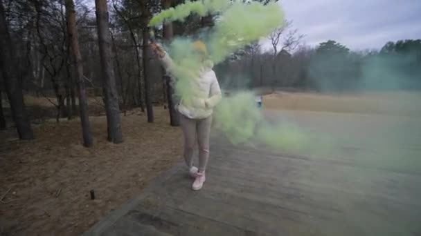 Une jeune fille joue avec la fumée colorée dans le parc. Torche avec fumée colorée — Video