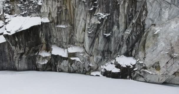凍った大理石の湖の近くの大理石の岩の上に垂直上昇-空撮 — ストック動画