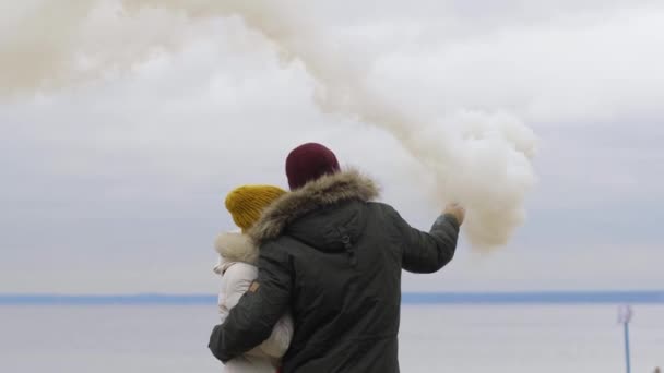 Una pareja en un abrazo en la orilla dejó salir humo de color. Luces de señal de rescate — Vídeos de Stock