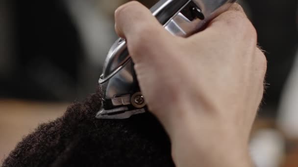 Το χορτοκοπτικό κόβει τα κατσαρά μαλλιά ενός Αφροαμερικανού - macro shot — Αρχείο Βίντεο