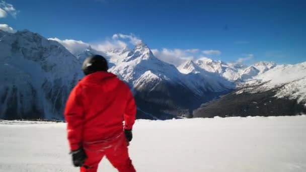 Un snowboarder con un traje de esquí naranja rueda a alta velocidad y cae en la pista — Vídeos de Stock