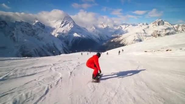 Сноубордист в помаранчевому лижному костюмі катається на високій швидкості і падає на колію — стокове відео