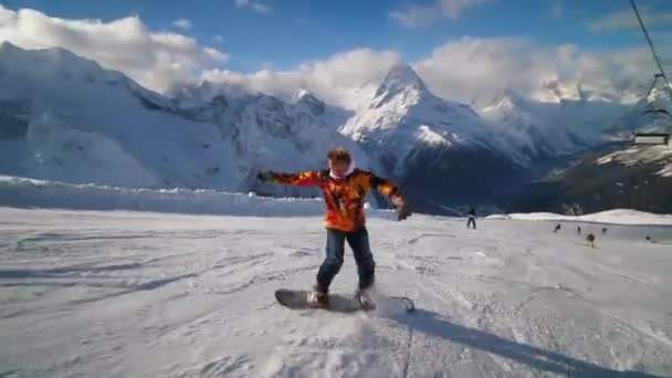 Un snowboarder a alta velocidad hace vueltas en una tabla de snowboard y muestra trucos — Vídeos de Stock