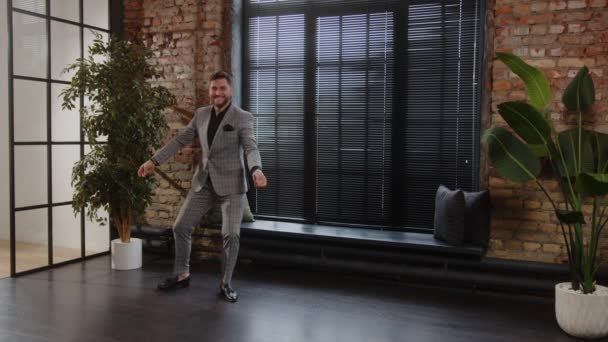 Boldog sikeres üzletember táncol és mosolyog egy drága szürke öltönyben. — Stock videók