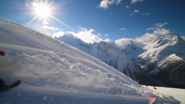 Snowboardzista w tęczowym stroju narciarskim toczy się z dużą prędkością i spada na tor — Wideo stockowe